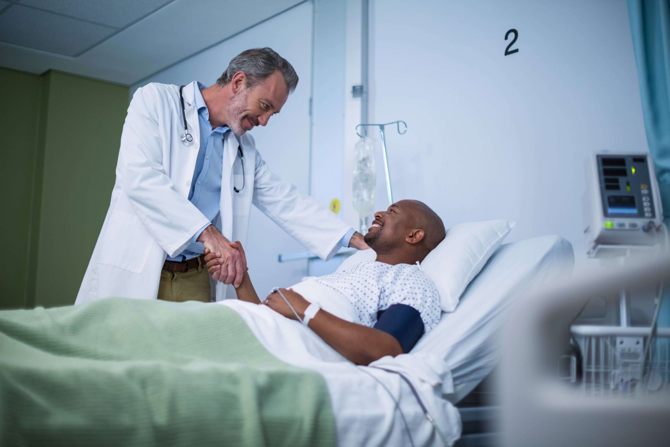 Clinician reassuring a patient at the bedside with a confident handshake—delivering trust and stability in critical care moments.